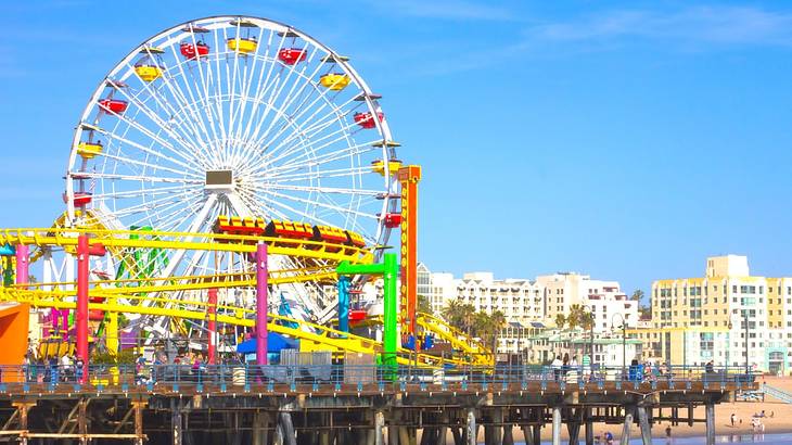 A colorful Ferris wheel and roller coaster on a pier