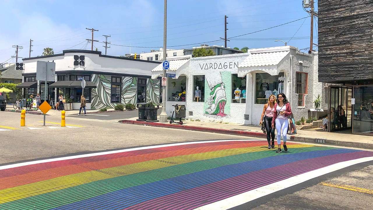A street with shops and a rainbow crosswalk painted on the road