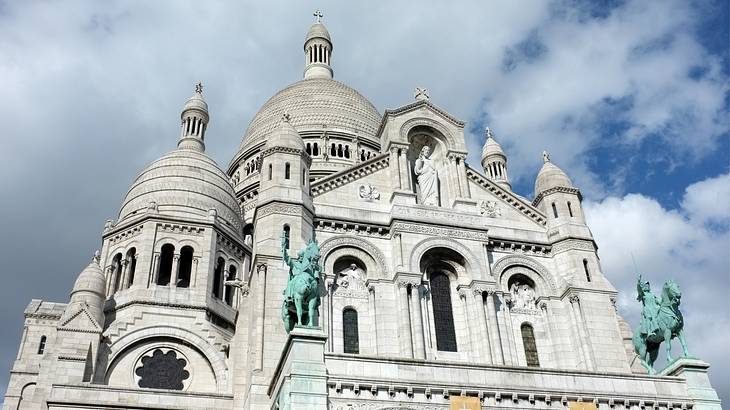 Close-up shot of Sacré-Cœur Basilica's facade from below on a partly cloudy day