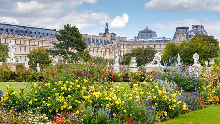 Colourful flowers with statues, trees and the Louvre Museum at the back Colourful flowers with statues, trees and the Louvre Museum at the back