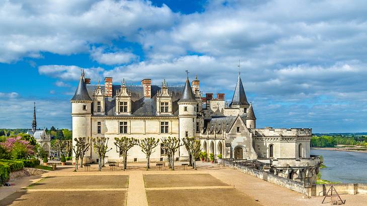 Château Royal d'Amboise under a cloudy blue sky with a river at its side