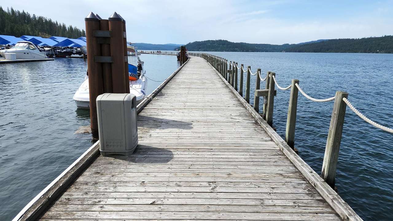 A boardwalk over water with a white boat moored on it under a somewhat cloudy sky