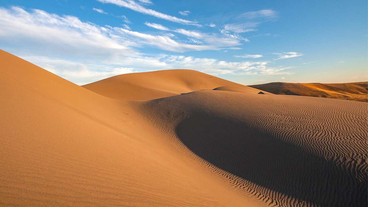 Hilly red sand dunes under a blue sky with white clouds