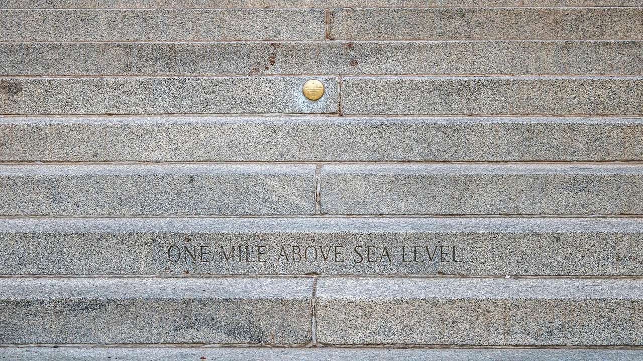 Engraving of "One Mile Above Sea Level" and a golden marker above on concrete steps