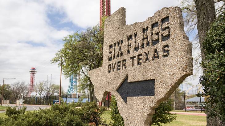 A sign shaped like Texas state that says "Six Flags Over Texas"