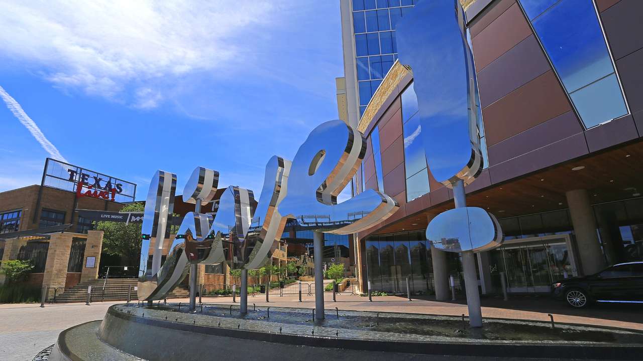 A mirrored sign that says "Live!" next to a brick building and a small square
