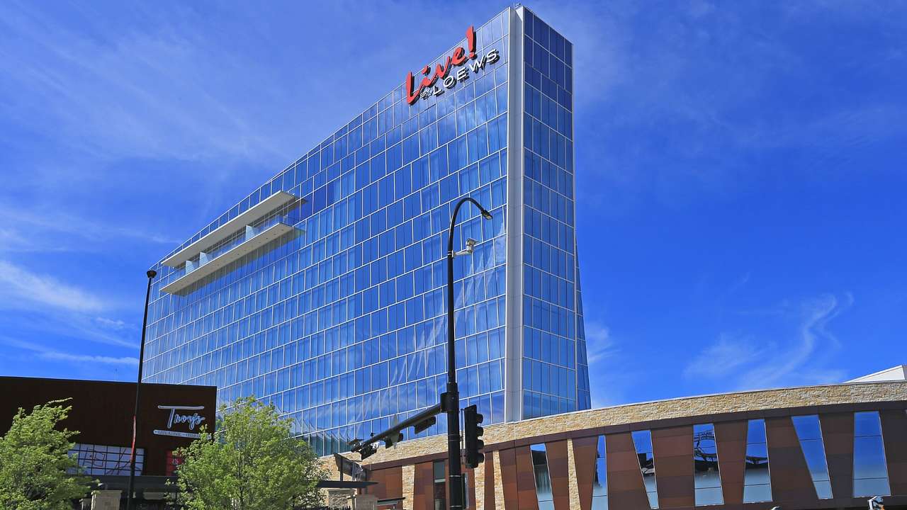 A tall glass building with a red sign that says "Live! by Loews"