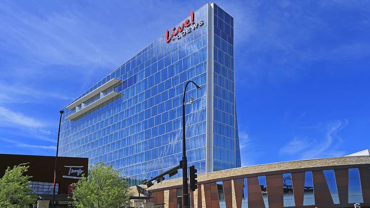 A tall glass building with a red sign that says "Live! by Loews"