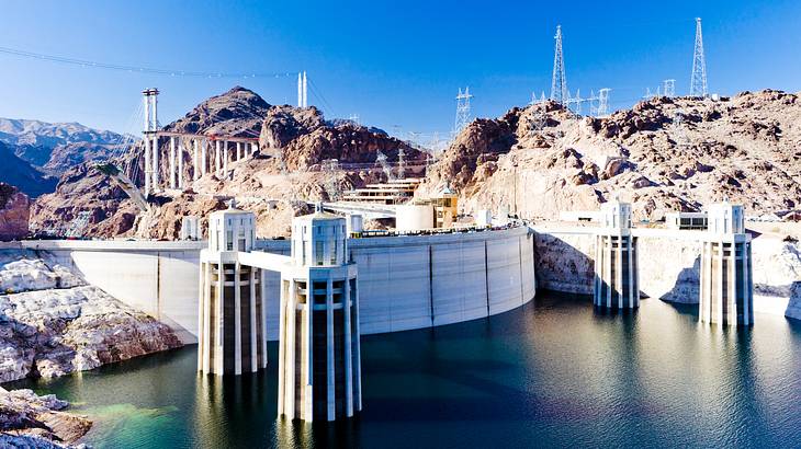 A large dam structure with water in front and mountains behind