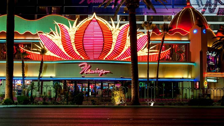 A pink neon lotus flower sign on a hotel at night