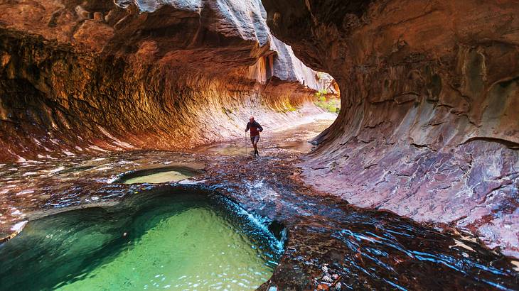 The inside of a canyon with water running through and a person hiking