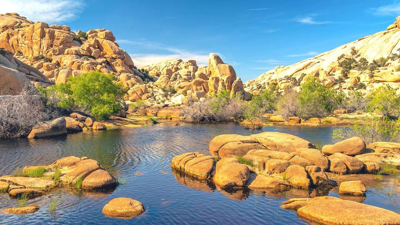 A pond with rocks in it and sandy-colored mountains around it