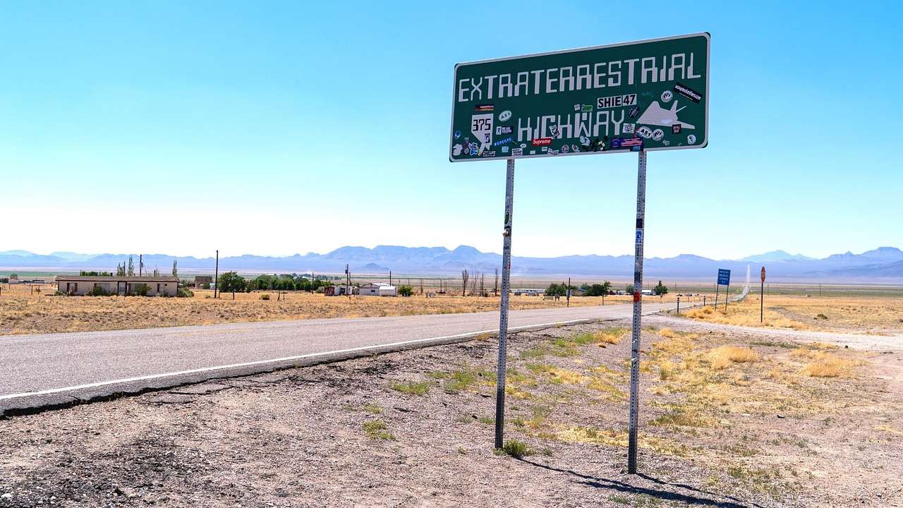 A green highway sign on the side of a road that says "Extraterrestrial Highway"