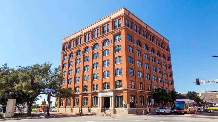 An orange-brick building with lots of windows and a street in front of it