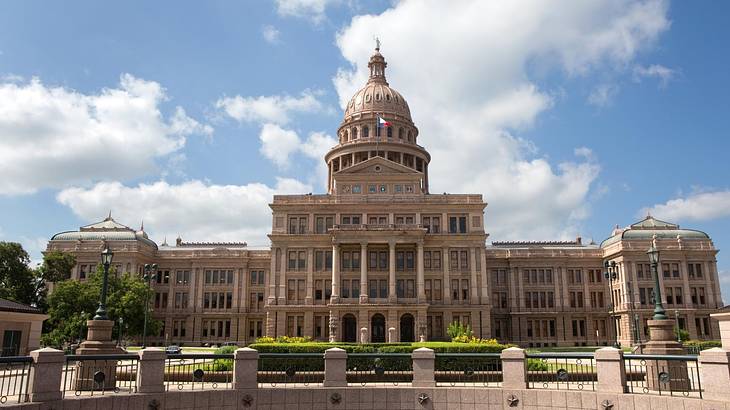 A State Capitol building with a rotunda roof and greenery in front of it