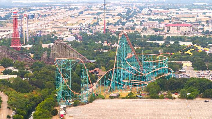 A rollercoaster with bushes and sandy land in the distance