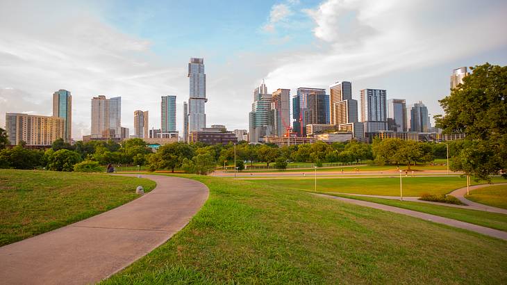 A path with grass on either side and a city skyline in the distance