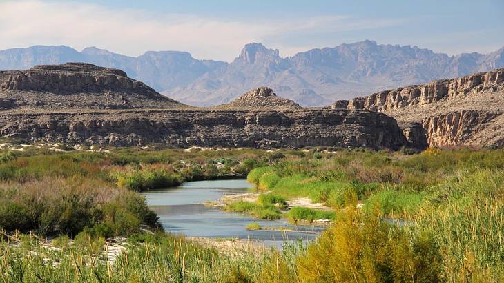 A river running through grassland with mountains in the background