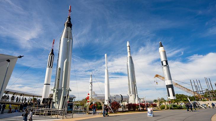 People wandering around a site with six space shuttles on a sunny day People wandering around a site with six space shuttles on a sunny day
