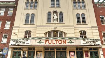The exterior of a stone theater building with a sign that says "Fulton"