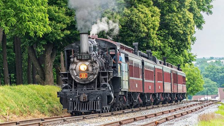 An old-fashioned locomotive on a track with green trees next to it