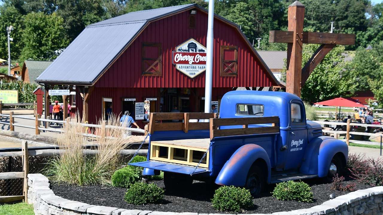 A blue model truck next to a red farm barn with a sign that says "Cherry Crest"