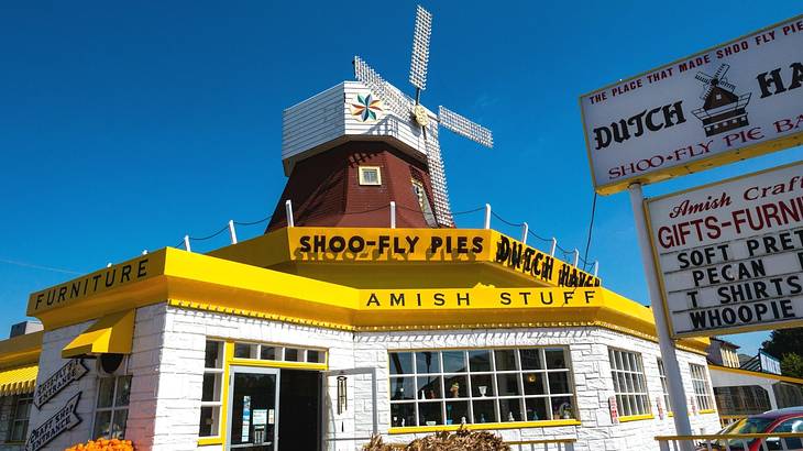 A yellow and white shop with a "shoo-fly pies" sign next to a windmill model
