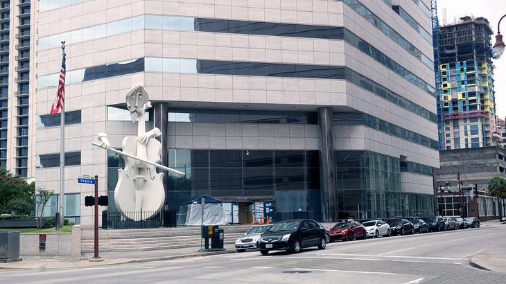 A tall sculpture of a man playing a violin beside a building
