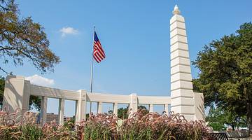 A stone monument and an American flag with a garden surrounding it