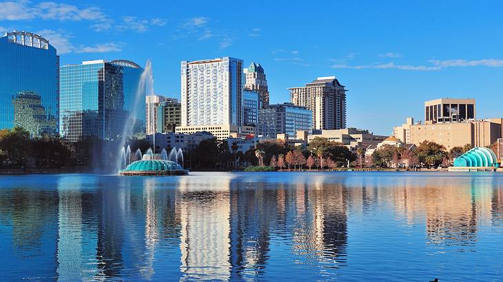 A body of water with a fountain and urban buildings at the back