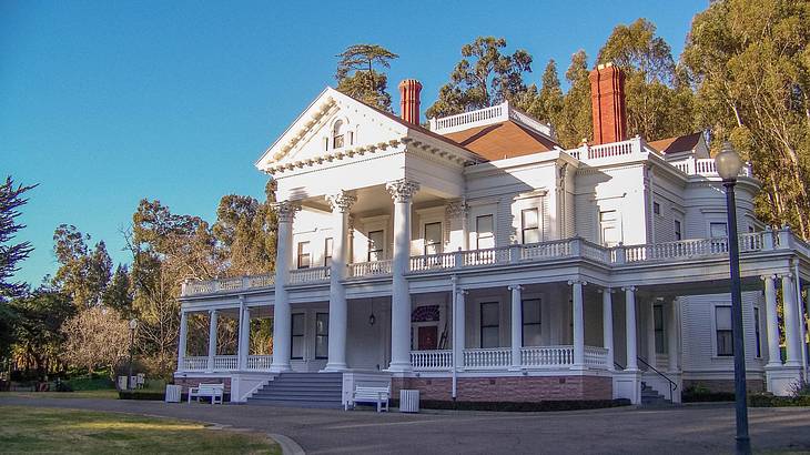 A large Neoclassical-style white house with a semi-circular driveway in front