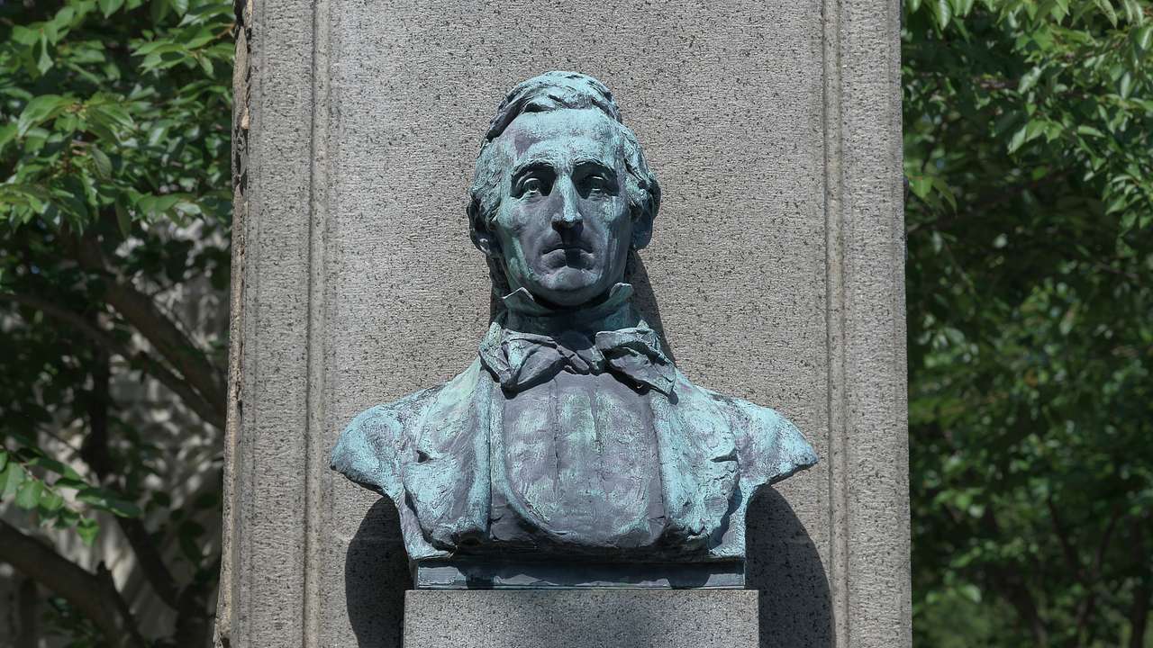A bust statue of a man with engraved letters on the base