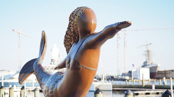 A statue of a mermaid next to a harbor