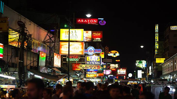 A view of a street at night with brightly lit signs and people walking