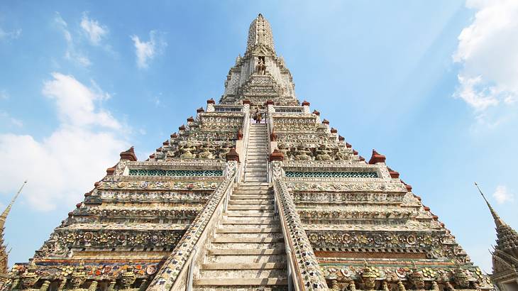 View of a temple with a staircase covered in carvings, under the blue sky, from below
