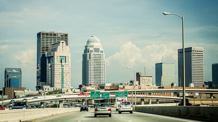 Cars driving a highway towards the city skyline in the background Cars driving a highway towards the city skyline in the background