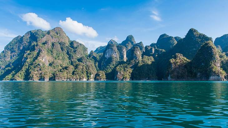 Body of blue water with vegetation-covered limestone cliffs in the background Body of blue water with vegetation-covered limestone cliffs in the background