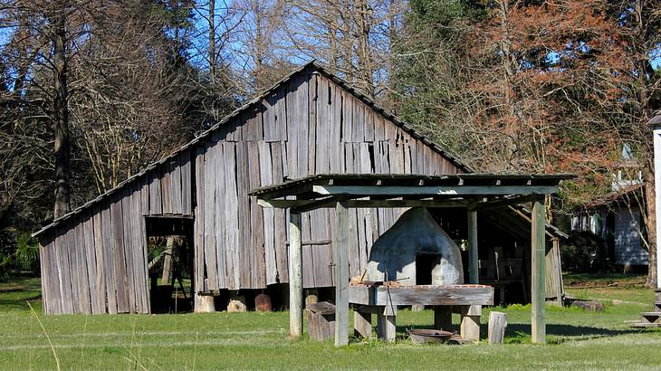 A small barn structure on the grass next to bare trees