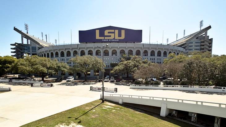 A football stadium with a sign that says "LSU" next to a road and grass