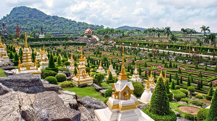 Landscaped garden full of temples, statues and greenery with a hill at the back