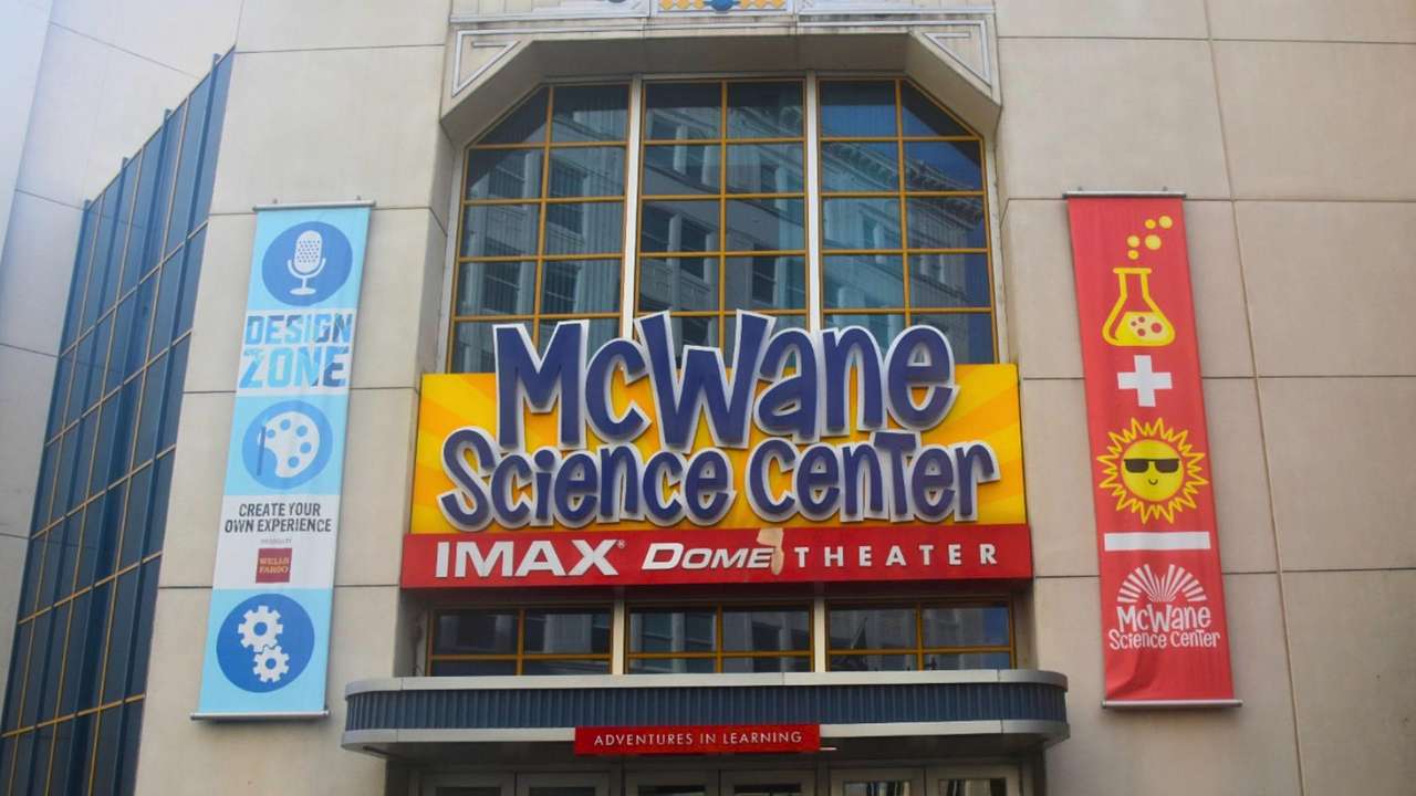 A sign that says "McWane Science Center" on a building with glass windows