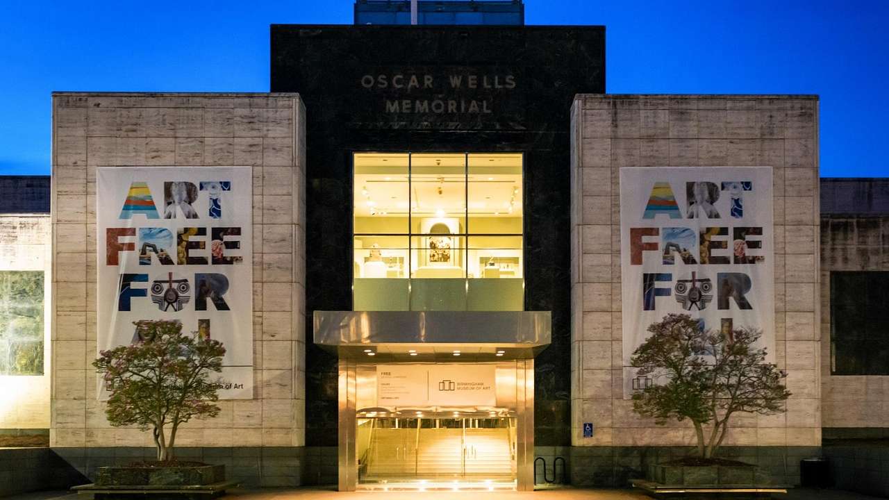 A modern building with banners and an "Oscar Wells Memorial" sign at night
