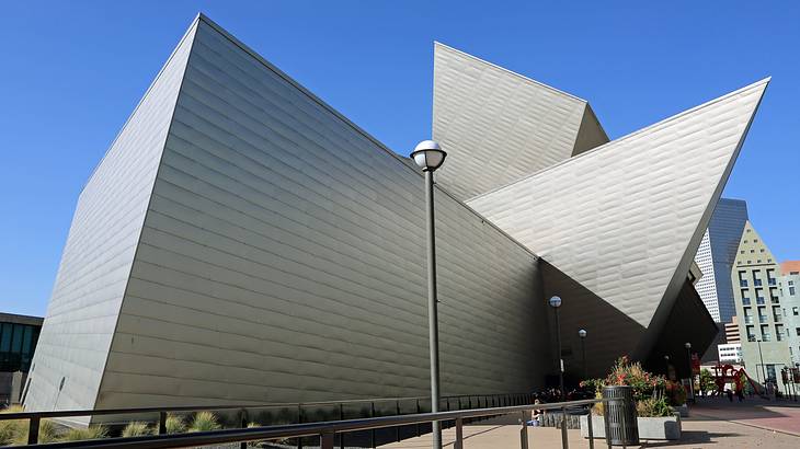 A gray modernist building next to a street under a blue sky