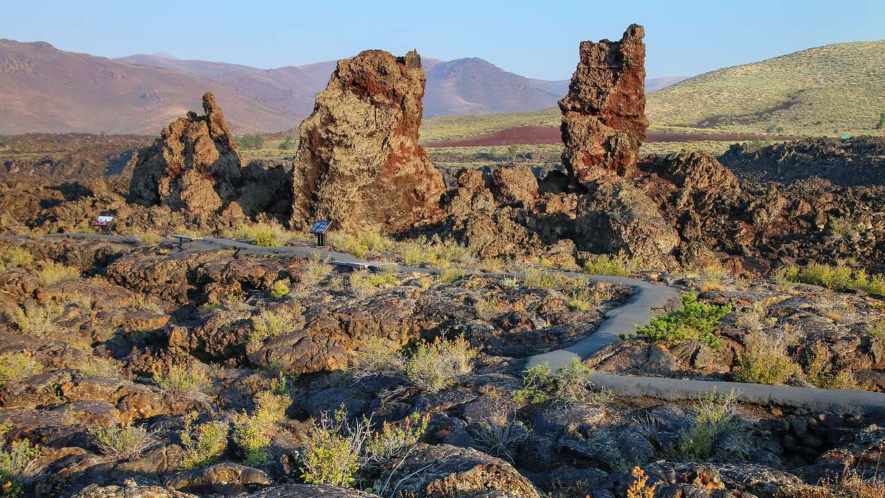 A narrow pathway winding through rugged landscapes of cinder cones and bushes