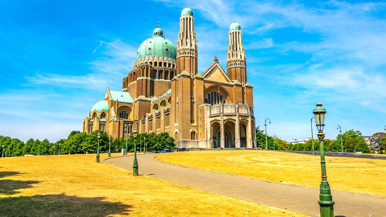 The outside of a basilica against a blue sky, facing a lawn with yellowing grass