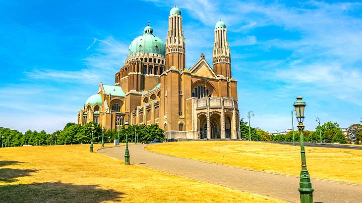 The outside of a basilica against a blue sky, facing a lawn with yellowing grass