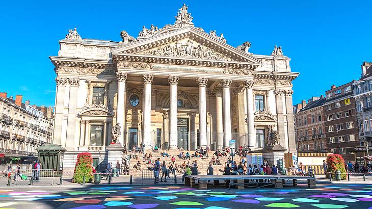 A building with baroque features and people and coloured shapes on the floor in front