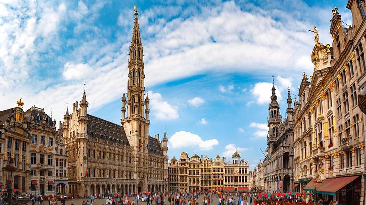 A Gothic town hall building with a lantern tower and tourists outside