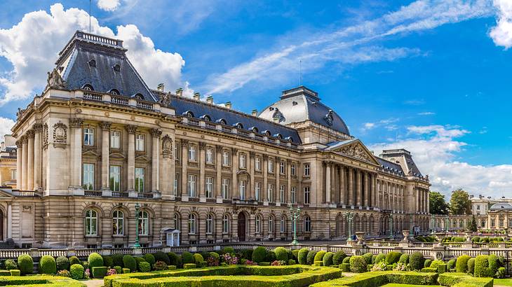 A neoclassical palace building with a gray roof under a partly cloudy sky