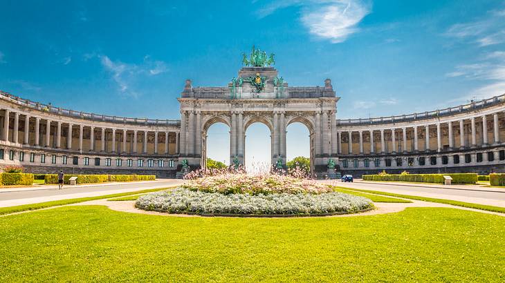 A triple arch gate with columns on each side and green grass in front of it